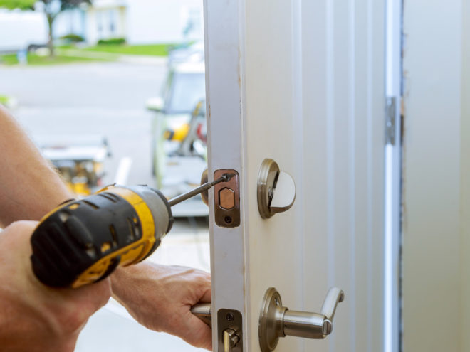 man repairing the doorknob. closeup of worker's hands installing new door locker